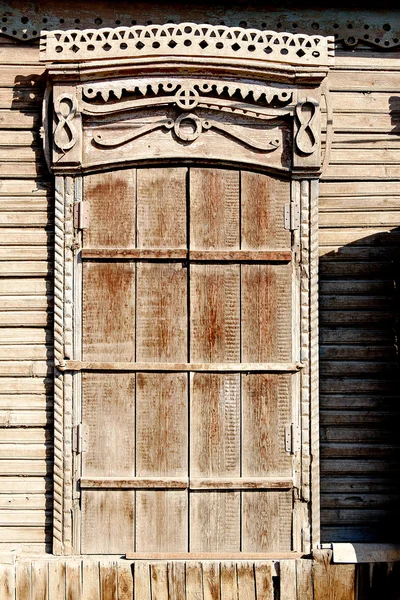 Invecchiato marrone serrande chiuse finestra di una vecchia casa baraccopoli in legno in Astrakhan, Russia — Foto Stock