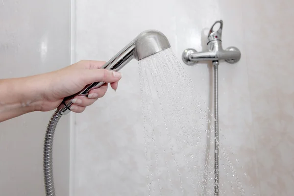 Womens hand holding shower head with pouring water in domestic bathroom, a lot of copyspace — Stock Photo, Image