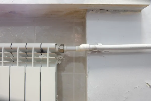 Parte do radiador moderno e tubo de plástico branco, um monte de espaço de cópia na parede — Fotografia de Stock