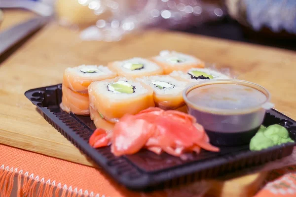 Open pack of sushi with soy sauce and ginger on the table, ready for eating — Stock Photo, Image