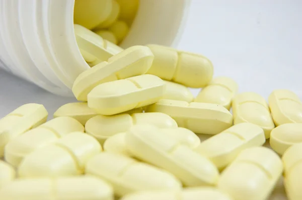 Yellow pills spilled out from bottle — Stock Photo, Image
