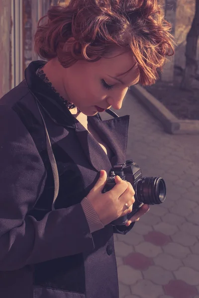 Vintage looking instagram style toned colors image of redhead women with camera in her hands — Stock Photo, Image