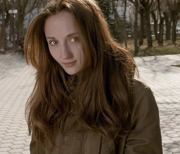 Portrait of young beautiful woman looking at camera in city park at fall or early spring — Stock Photo, Image