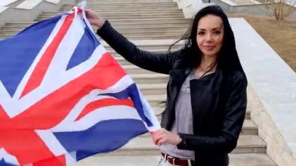 Brunetka kobiet z flagą Uk Union Jack pozowanie uśmiechający się na zewnątrz. Pozytywny latino kobiet. — Wideo stockowe