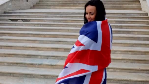 Sexy brunette warped in UK Union Jack flag waving by the wind. — Stock Video