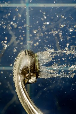 Su akışı ile duş başlığı mavi backg üstünde havaya kaldırmak