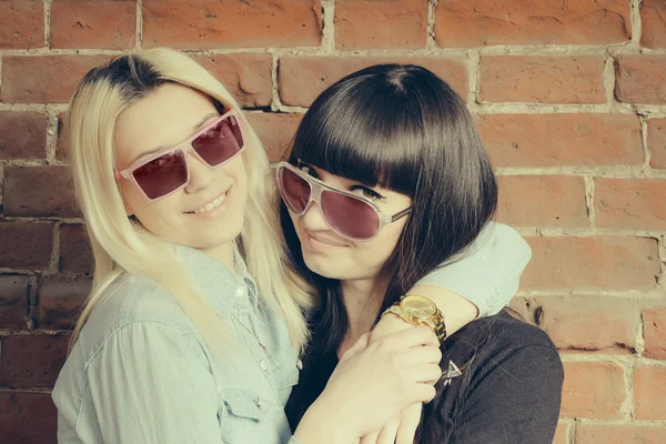 Закройте модный портрет двух девочек, обнимающихся и веселящихся вместе, надевая стильные солнцезащитные очки, и наслаждайтесь прекрасным временем вместе . — стоковое фото