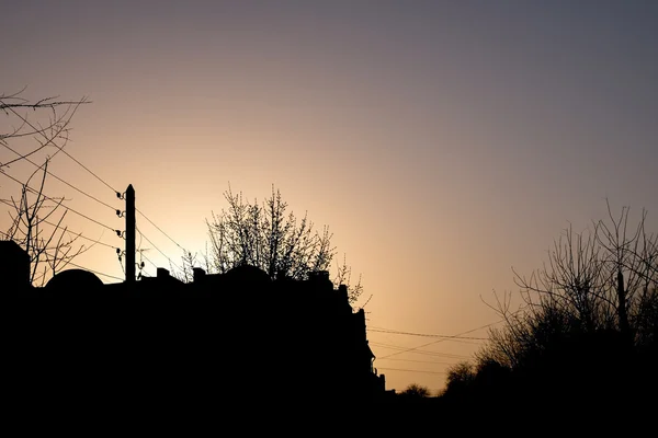 Scène rurale de couleur vanille - silhouette de la maison, des arbres et des fils contre le lever du soleil — Photo