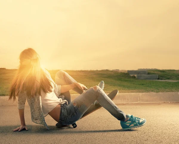 Молодая девушка падает со скейтборда подсветкой на закате — стоковое фото