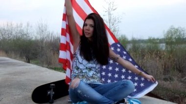 Amerikan bayrağı ve oturan kaykay ile poz casual trendy kız görüntüleri açık havada bacak bacak.
