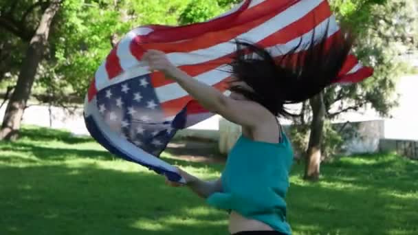 Hermosa joven patriótica con la bandera americana sostenida en sus manos bailando slow mo — Vídeos de Stock