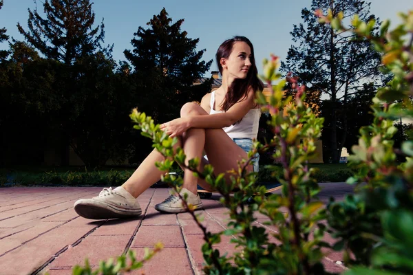 Frauen sitzen auf Skateboard und blicken zurück — Stockfoto