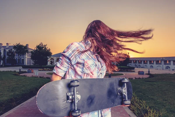 Mujeres jóvenes con skatebord sacudiendo su pelo rojo — Foto de Stock