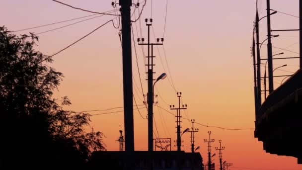 Colorful sunset with a bridge and street lamp silhouettes over — Stock Video