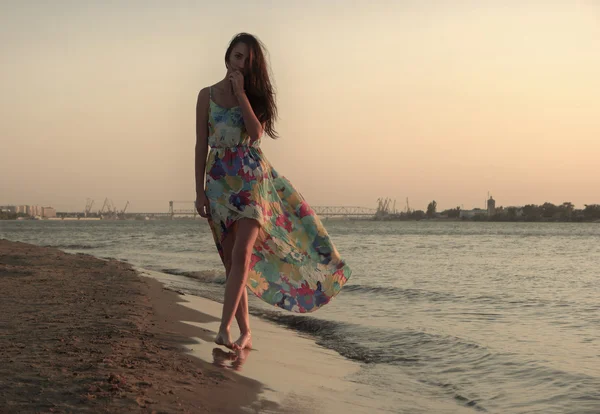 Jovem mulher em um vestido colorido na costa do oceano — Fotografia de Stock