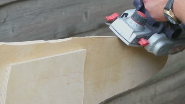 Man een plank van hout in zijn Houtklas schooljaar schaven met een vliegtuig vloeiend op de rand. Man geschaafd bord met elektrische planer — Stockvideo