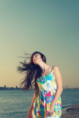 Waist Up Shot of Young Women on Seaside with wind fluttering her hair clipart