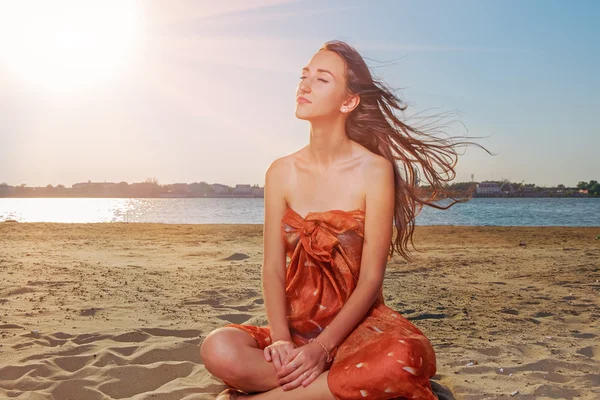 Las mujeres jóvenes meditan en la playa junto al mar con los ojos cerrados retroiluminados por el sol, espacio para copiar —  Fotos de Stock