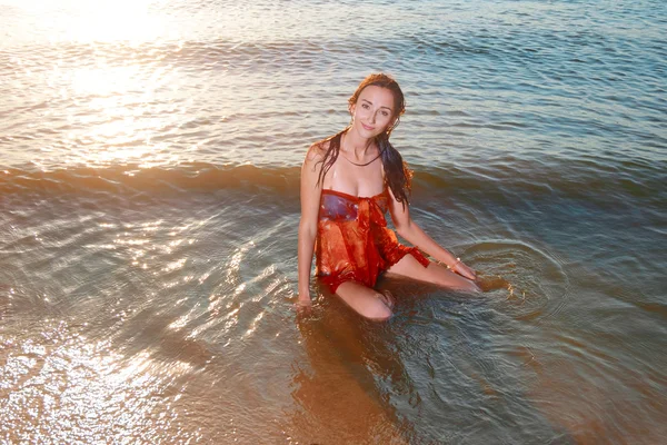 Junge schöne Rothaarmädchen in azurblauem Bikini und orangefarbener Tunika posiert am Strand — Stockfoto