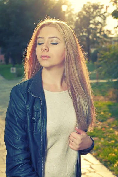 Jovem mulher pensativa com os olhos fechados posando ao ar livre retroiluminado pelo sol de outono — Fotografia de Stock