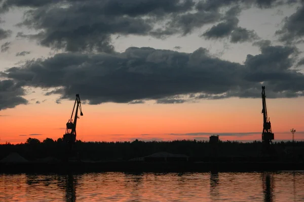 Salida del sol sobre el Volga-río y grúas portuarias en el cielo — Foto de Stock