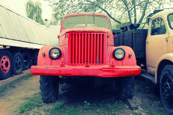 Παλιό σκουριασμένο κόκκινο αγρόκτημα φορτηγά ξεθώριασμα στο χρόνο έχει πρόσοψη. — Φωτογραφία Αρχείου