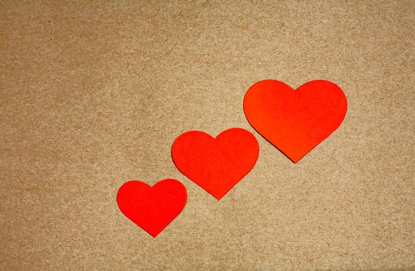 Três corações vermelhos sobre papel artesanal com espaço de cópia. Cartão para um dia dos namorados . — Fotografia de Stock