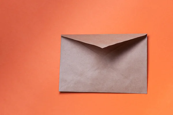 Brauner Umschlag auf orangefarbenem Hintergrund, Kopierraum. — Stockfoto