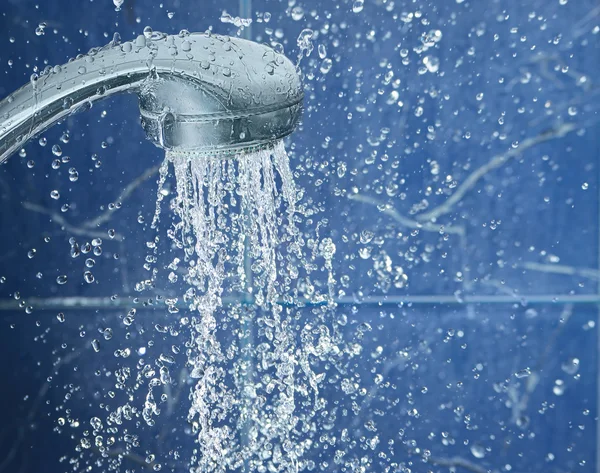 Chuveiro em fundo azul com gotas de água voar no ar, imagem com espaço para texto à direita — Fotografia de Stock