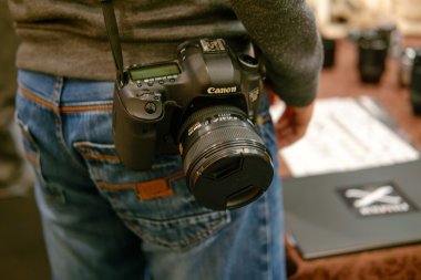 Astrakhan, Rusya - 07 Aralık 2015: Fotoğrafçı ile logo karşı Canon ayna dijital fotoğraf makinesi. Fujifilm teknolojik aynasızlar kamera pazarında liderdir
