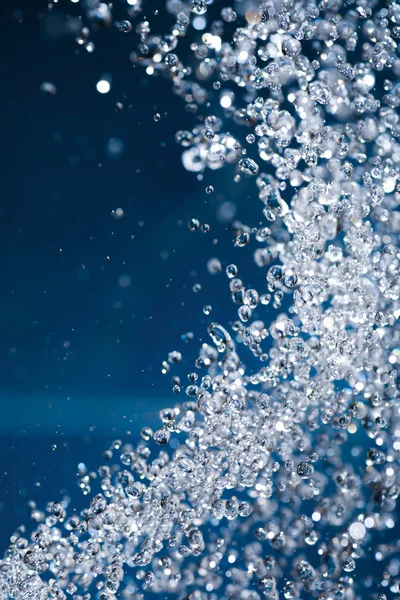 Gebogen blauw splash van waterdrops schieten close-up — Stockfoto