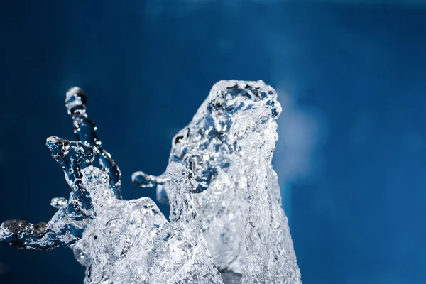 Water splash levitating in the air on blue — Stock Photo, Image
