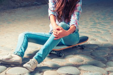 Scateboard ve boşaltmak üzerinde oturan kız