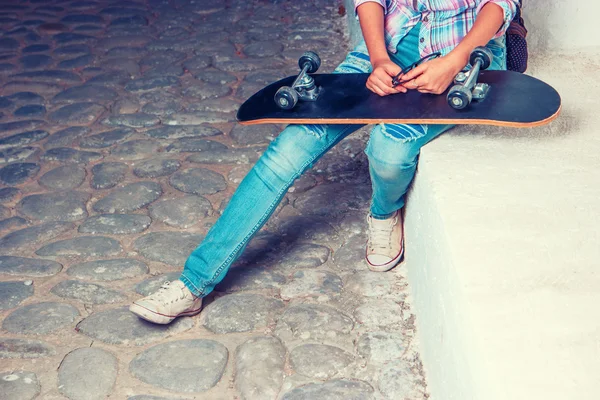 Дівчина з скейтбордом на колінах і копійкою — стокове фото