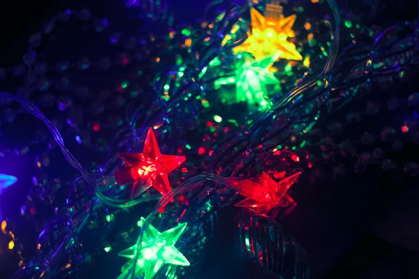 Decorazione di Natale e Capodanno offuscata. Ghirlanda stellata. Vacanza sfondo incandescente. DOF poco profondo — Foto Stock