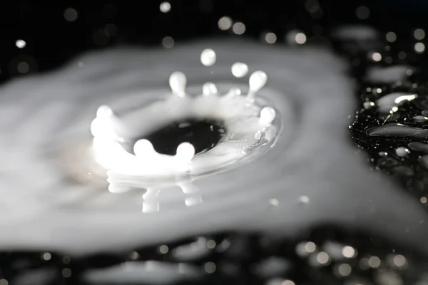 Gota de leite salpicando sobre a superfície escura — Fotografia de Stock