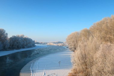 Nehir ve ağaçlarla kaplı kış manzarası
