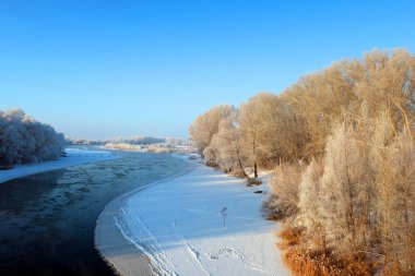 Nehir ve ağaçlarla kaplı kış manzarası