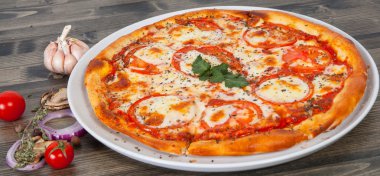 İtalyan pizza domates erimiş altın peynir, otlar ve ahşap masa üzerinde fesleğen ile tepesinde ile