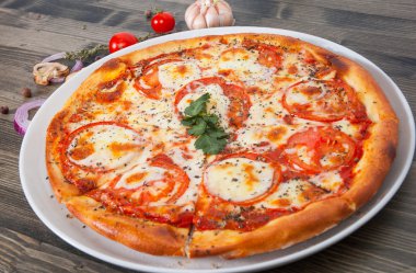 İtalyan pizza domates erimiş altın peynir, otlar ve ahşap masa üzerinde fesleğen ile tepesinde ile