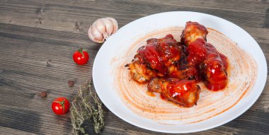 Ahşap masa üzerinde kırmızı domates soslu tavuk kanadı