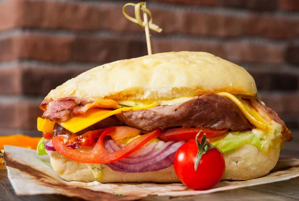Burger mit Fleisch, Tomaten, Zwiebeln, Käse, Salat, Gemüse auf Holztisch — Stockfoto