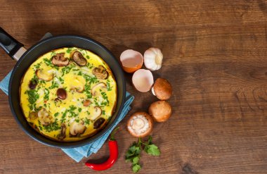 ahşap masa üzerinde bir tavada mantarlı omlet