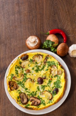 ahşap masa üzerinde bir tabak mantarlı omlet