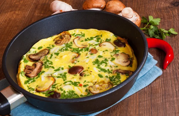 ahşap masa üzerinde bir tavada mantarlı omlet