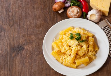ahşap masa üzerinde bir tabak içinde peynirli rigatoni makarna