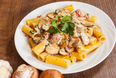 ahşap masa üzerinde bir tabak içinde mantar soslu makarna Rigatoni