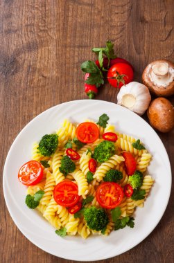 Düdük makarna domates ve brokoli ahşap masa üzerinde bir plaka ile