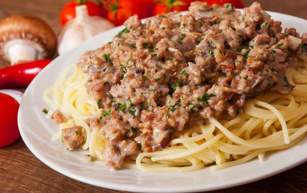 A gomba és a darált húst a fából készült asztal egy tányér spagettit — Stock Fotó
