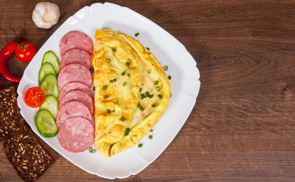 Omelett mit Salami in einem Teller auf Holztisch — Stockfoto